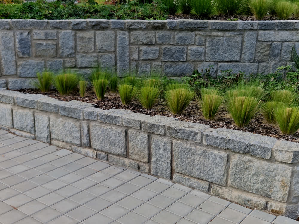 Tiered stone retaining wall with varied block sizes and planting